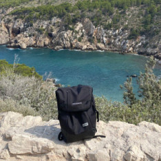 Backpack in the foreground with a lake in the background, surrounded by small cliffs