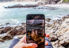 Image in the point of view of a user taking a picture of their feet on some rocks near the sea