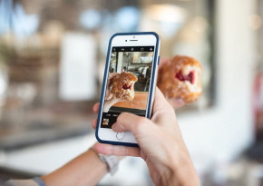 Person taking a picture of a pastry they are holding