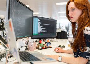 Woman in office programming on her laptop and two extra monitors