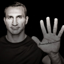 Man showing the palm of his hand to the camera. The palm has the tag #WeAreAllUkrainians